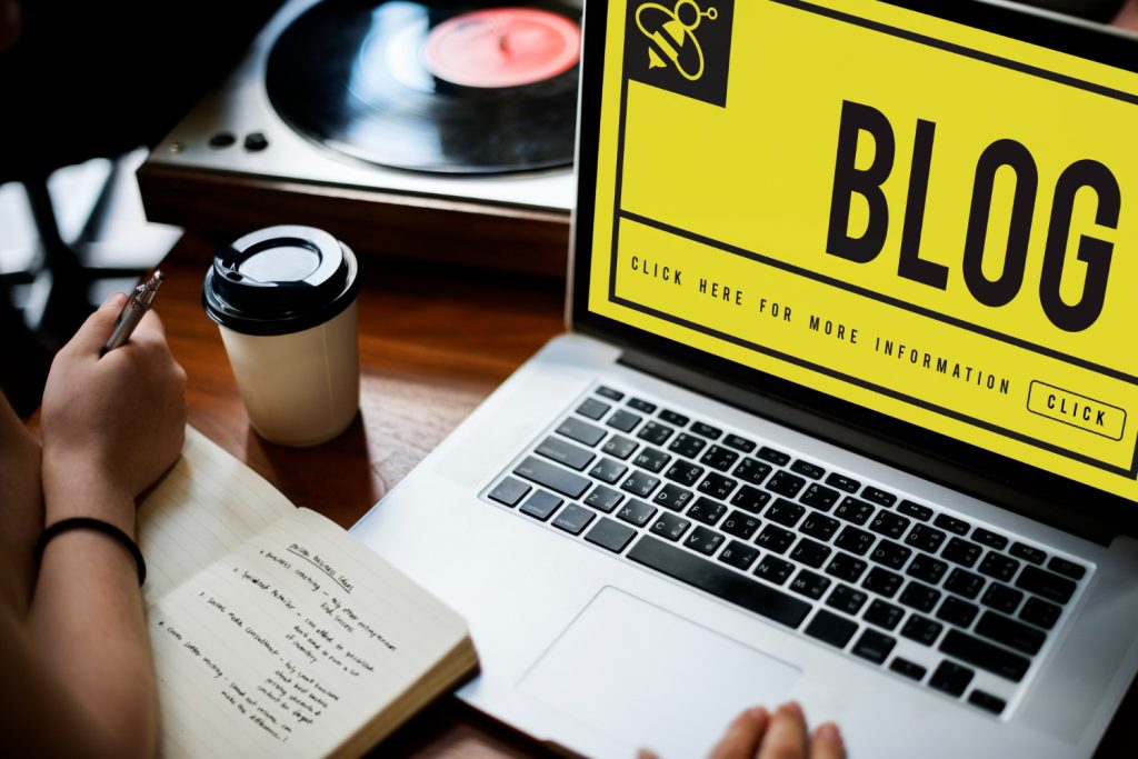 Laptop screen displaying "Blog" beside a notebook
