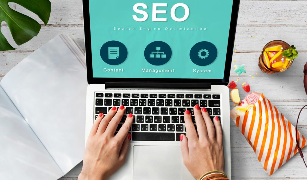 Hands typing on a laptop with SEO graphics